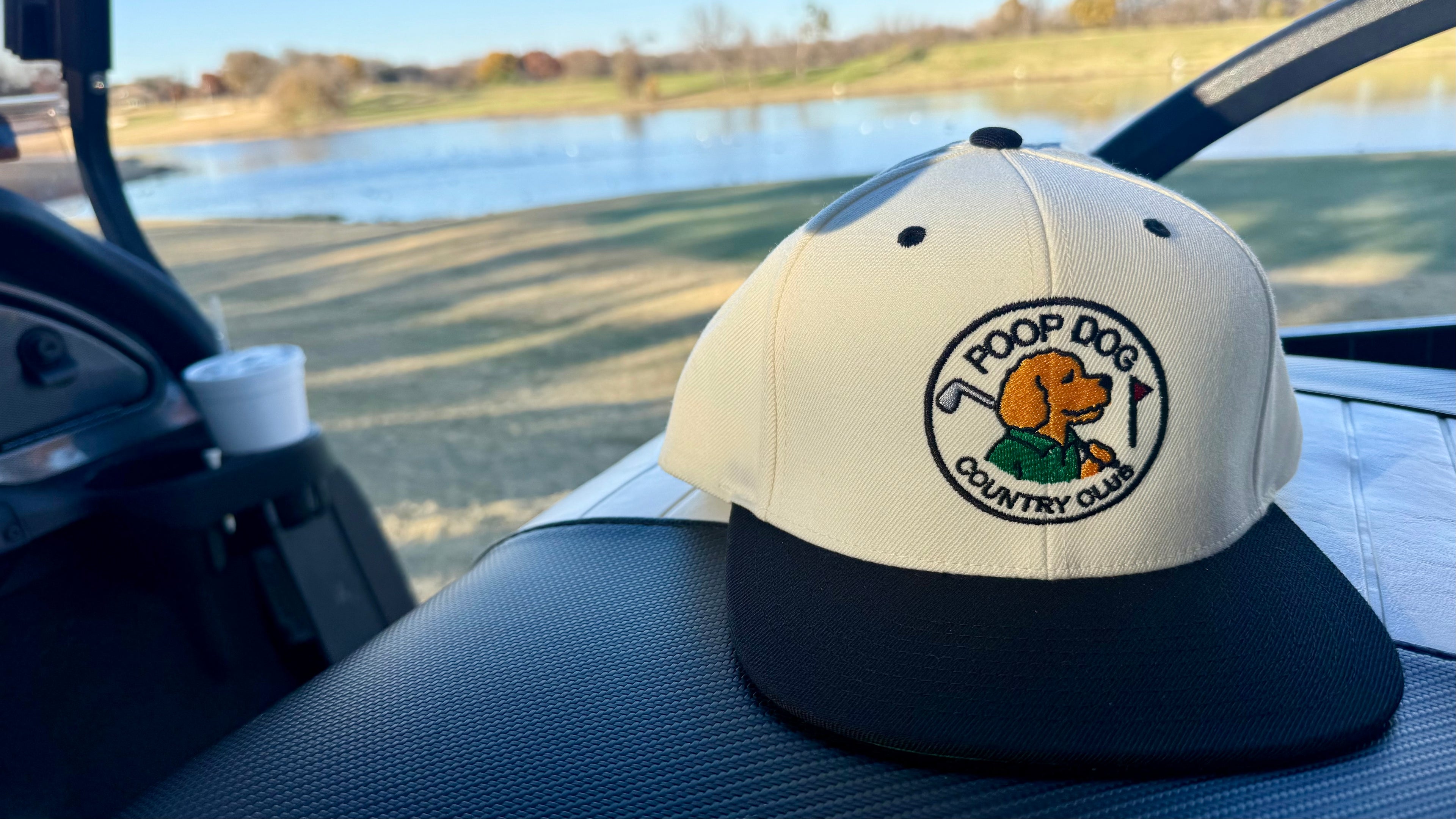 Cap with a logo on a car seat, with a scenic background of water and grass.